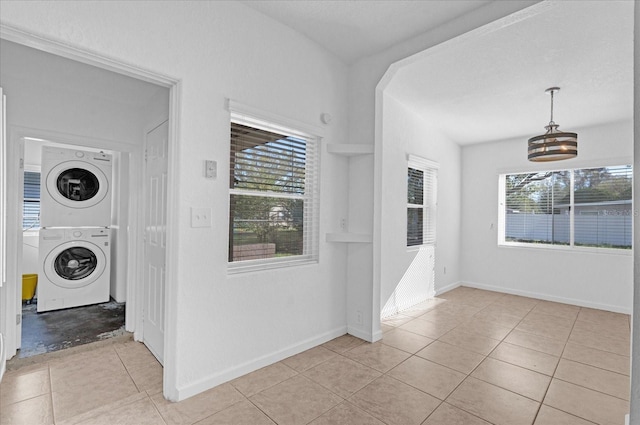 interior space featuring light tile patterned floors, baseboards, and stacked washer / drying machine