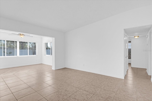 spare room featuring light tile patterned floors, baseboards, and ceiling fan