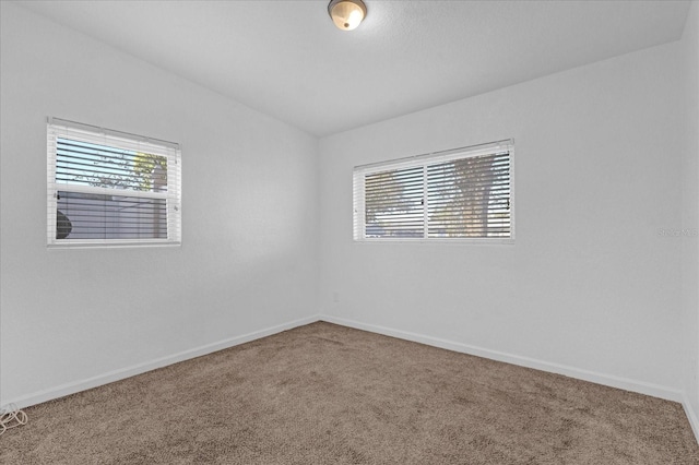 carpeted empty room featuring plenty of natural light and baseboards