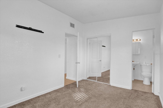 unfurnished bedroom with visible vents, connected bathroom, baseboards, carpet floors, and a closet