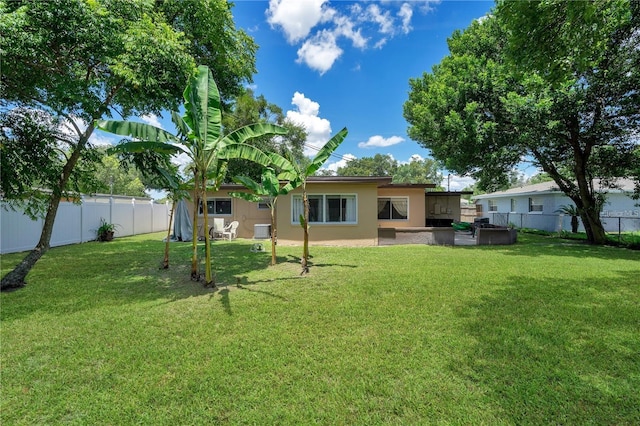 rear view of property with a yard, a fenced backyard, and stucco siding