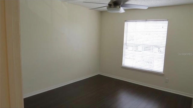 unfurnished room featuring dark wood-style floors, baseboards, and a ceiling fan