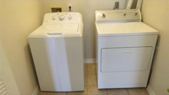 laundry room featuring laundry area, baseboards, and washing machine and clothes dryer