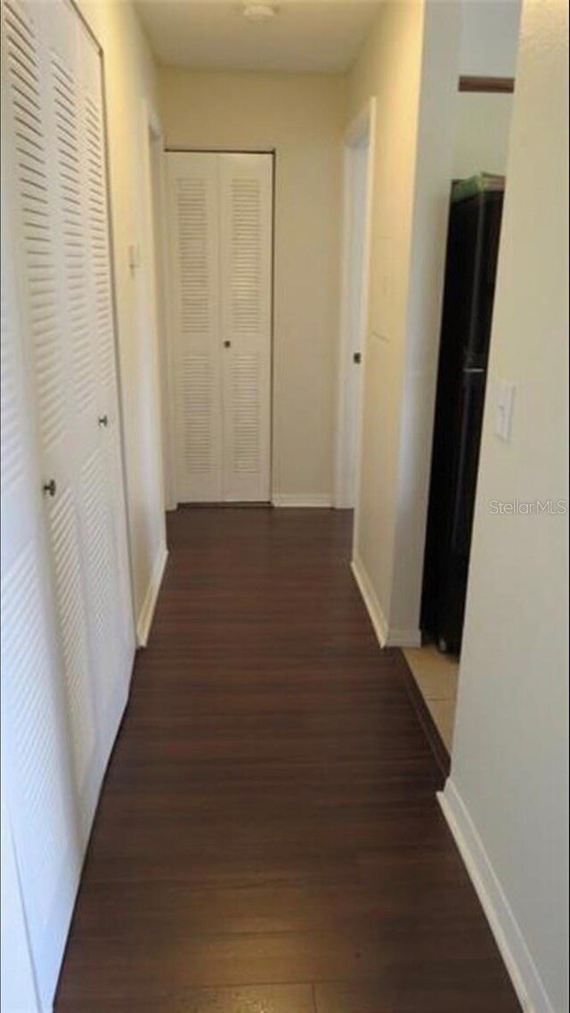corridor with baseboards and wood finished floors