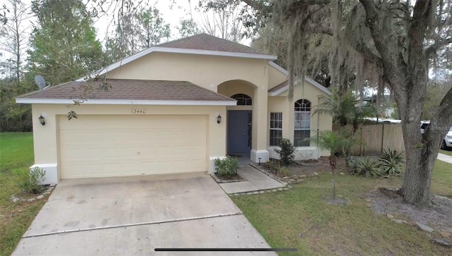 single story home with stucco siding, a shingled roof, concrete driveway, an attached garage, and a front lawn