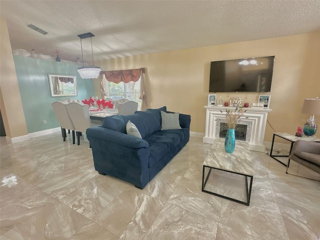 living room featuring marble finish floor, visible vents, a fireplace with raised hearth, and a textured ceiling