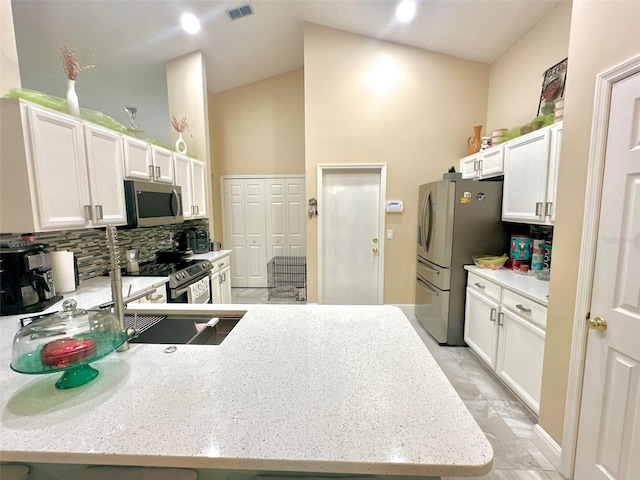 kitchen featuring stainless steel appliances, a peninsula, visible vents, white cabinetry, and tasteful backsplash