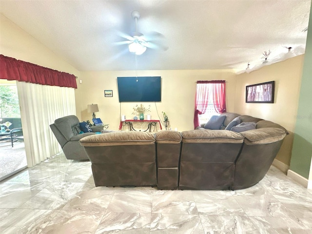 living area featuring lofted ceiling, marble finish floor, a ceiling fan, and a textured ceiling