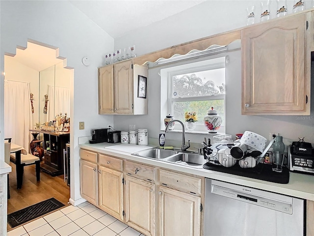 kitchen featuring light brown cabinetry, a sink, light countertops, dishwasher, and vaulted ceiling