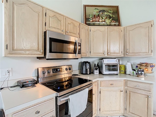 kitchen with tile patterned flooring, light countertops, a toaster, and appliances with stainless steel finishes