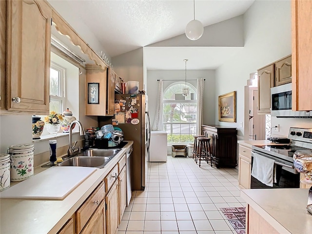 kitchen featuring a sink, stainless steel appliances, light countertops, and vaulted ceiling