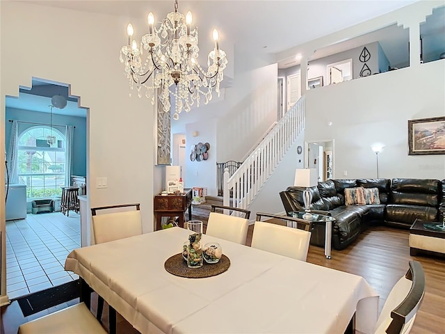 dining area featuring stairway, wood finished floors, a notable chandelier, and a towering ceiling