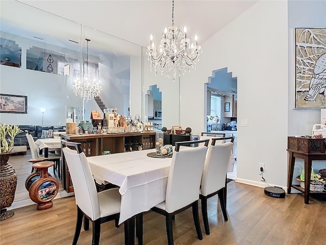 dining room with a high ceiling, an inviting chandelier, and wood finished floors