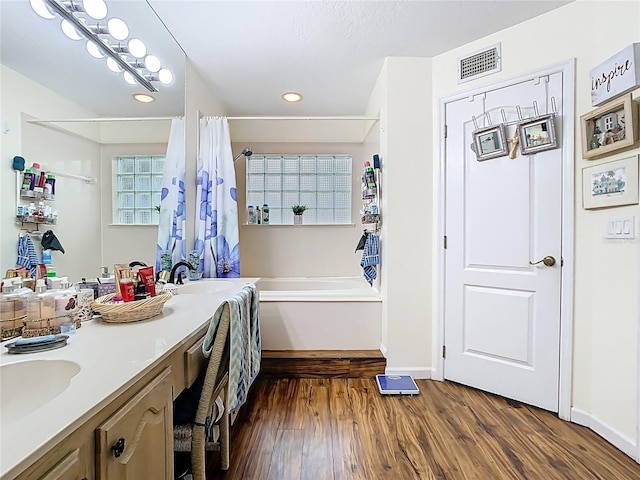 full bathroom with vanity, a shower with shower curtain, wood finished floors, visible vents, and a bathtub