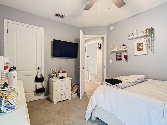 bedroom with light carpet, visible vents, and a ceiling fan