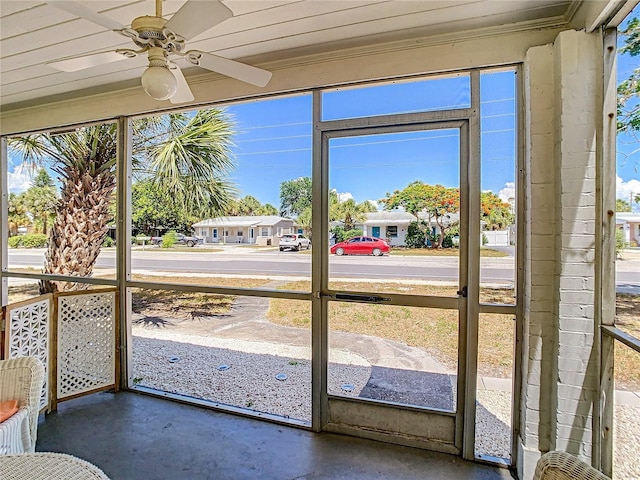 unfurnished sunroom featuring a residential view and ceiling fan