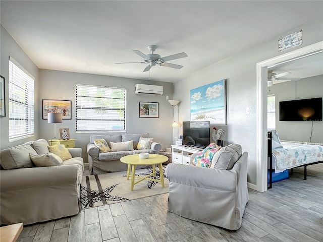 living area featuring a wall mounted air conditioner, baseboards, a ceiling fan, and light wood finished floors