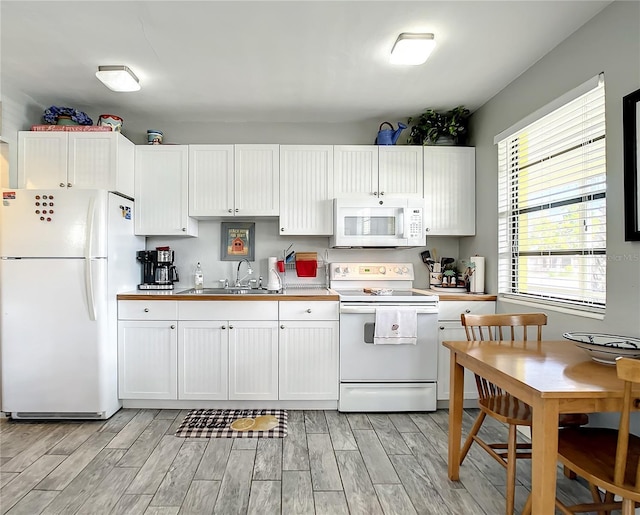 kitchen with a sink, white appliances, white cabinets, and wood tiled floor