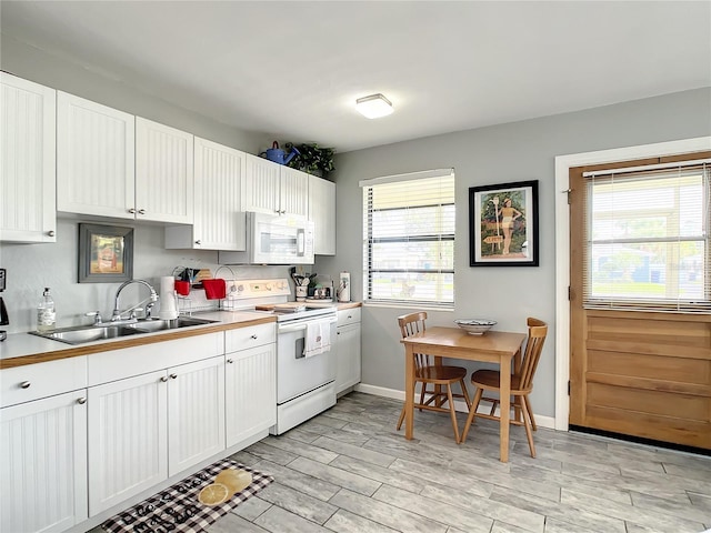 kitchen featuring white cabinetry, white appliances, plenty of natural light, and a sink