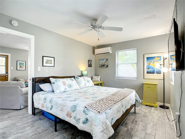 bedroom with multiple windows, a wall mounted air conditioner, light wood-type flooring, and a ceiling fan