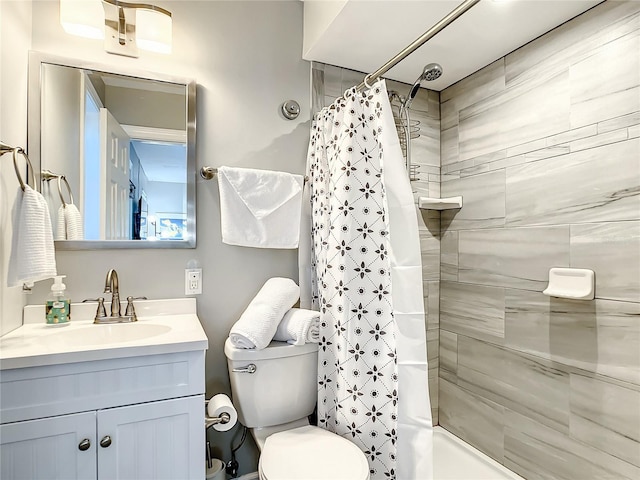 full bathroom with a tile shower, toilet, and vanity