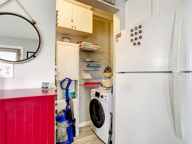 clothes washing area with washer / dryer, laundry area, and light wood finished floors