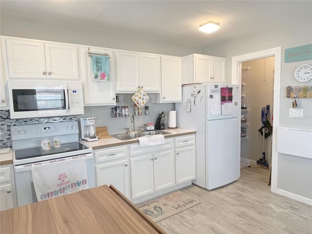 kitchen featuring a sink, white appliances, light countertops, and white cabinetry