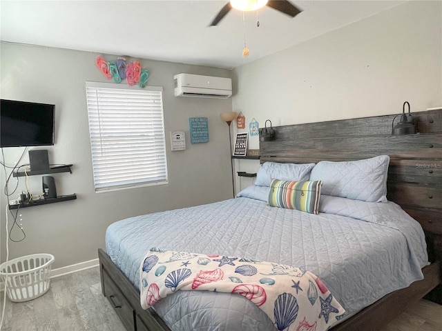 bedroom featuring a wall mounted air conditioner, baseboards, wood finished floors, and ceiling fan