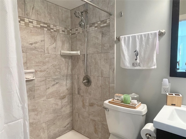 bathroom featuring tiled shower, toilet, and vanity