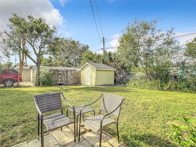 view of yard featuring a storage shed, an outbuilding, a fenced backyard, and a patio