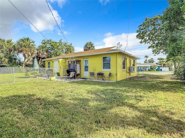 rear view of property with stucco siding, a patio, a yard, and fence