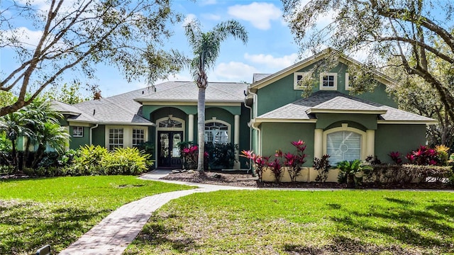 view of front of house featuring stucco siding, french doors, a front lawn, and roof with shingles