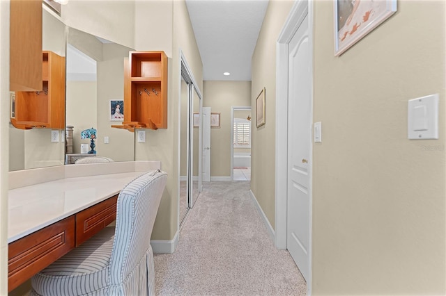 hallway featuring light carpet and baseboards