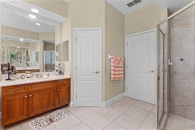 bathroom with tile patterned floors, visible vents, a shower stall, and vanity