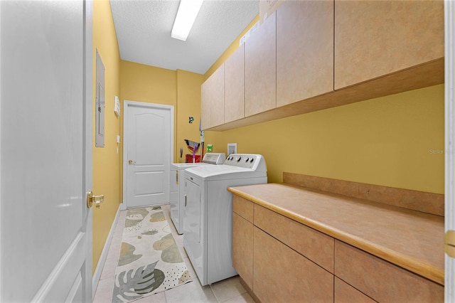 laundry area featuring washer and dryer, light tile patterned floors, cabinet space, and a textured ceiling