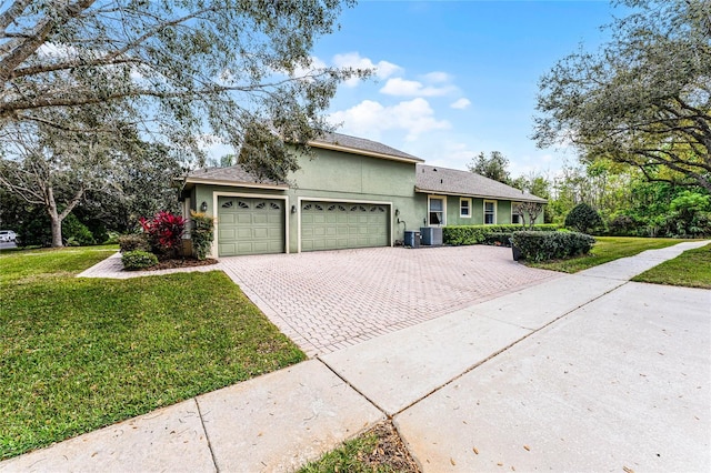 single story home featuring a shingled roof, a front yard, stucco siding, decorative driveway, and an attached garage