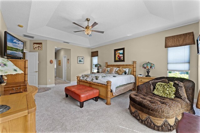 bedroom featuring visible vents, a raised ceiling, a ceiling fan, carpet floors, and baseboards