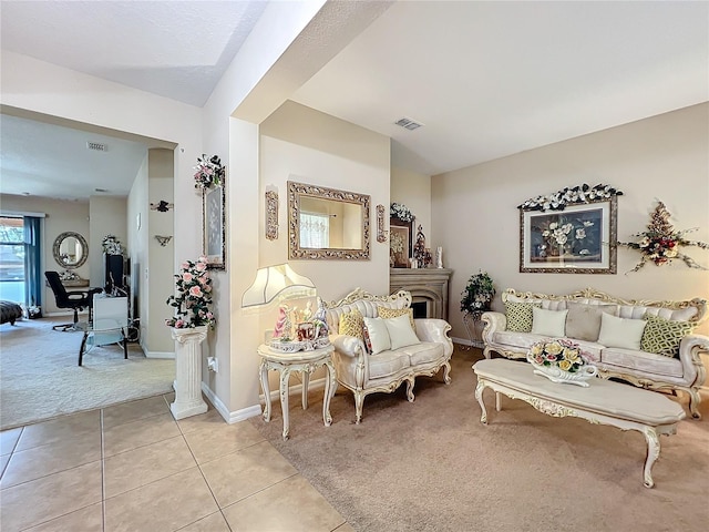 living area with light carpet, light tile patterned floors, visible vents, and baseboards