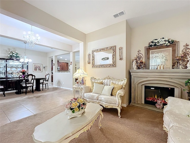 living area featuring light tile patterned floors, light colored carpet, visible vents, an inviting chandelier, and a glass covered fireplace