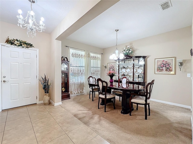 dining room with light colored carpet, visible vents, light tile patterned flooring, and an inviting chandelier