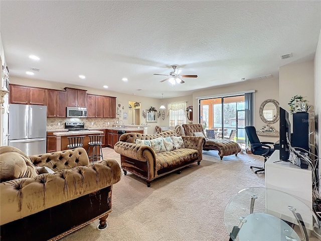 living room featuring light carpet, visible vents, a textured ceiling, and recessed lighting