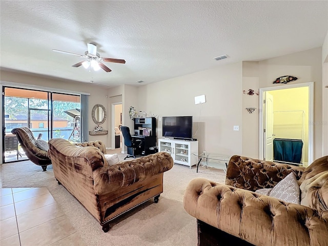 living area with a textured ceiling, ceiling fan, light tile patterned floors, and visible vents