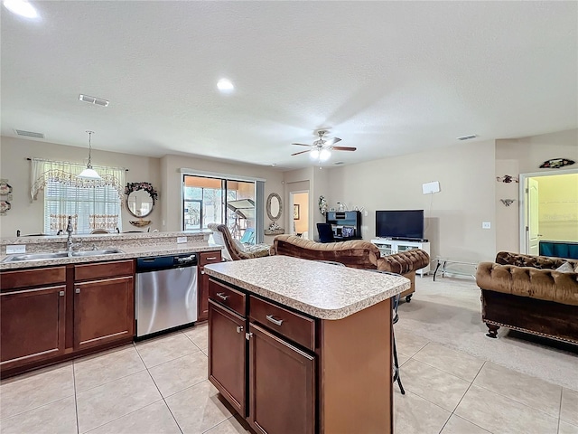 kitchen with light countertops, visible vents, stainless steel dishwasher, open floor plan, and a sink