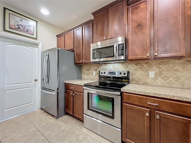 kitchen with light tile patterned floors, appliances with stainless steel finishes, light countertops, and backsplash