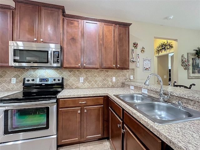 kitchen featuring stainless steel appliances, tasteful backsplash, a sink, and light countertops