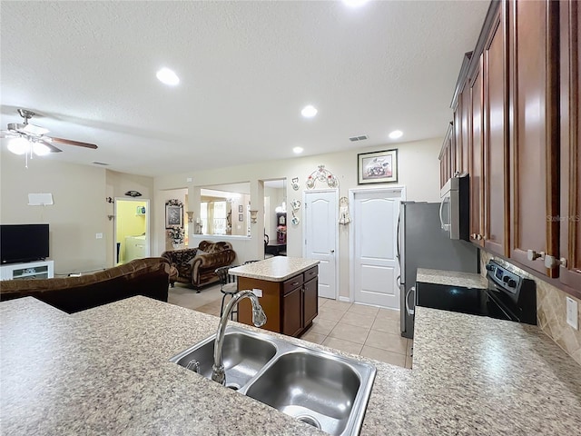 kitchen featuring appliances with stainless steel finishes, a center island, open floor plan, and a sink