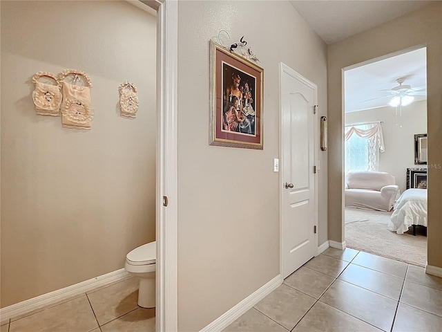 interior space with toilet, ensuite bathroom, ceiling fan, baseboards, and tile patterned floors