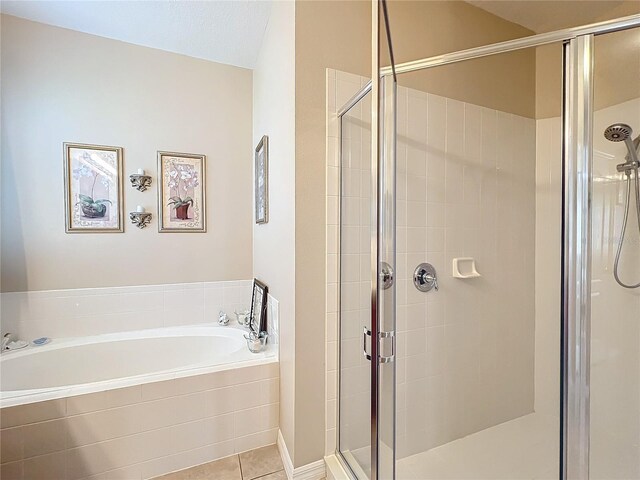 bathroom with a stall shower, tile patterned flooring, and a bath