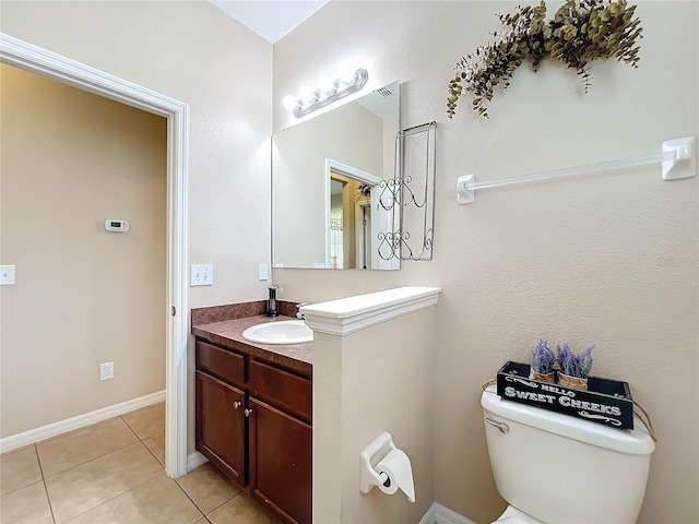 half bath with tile patterned flooring, baseboards, vanity, and toilet