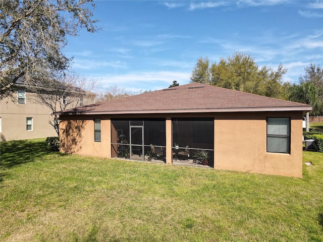 rear view of property with a yard, roof with shingles, a sunroom, and stucco siding